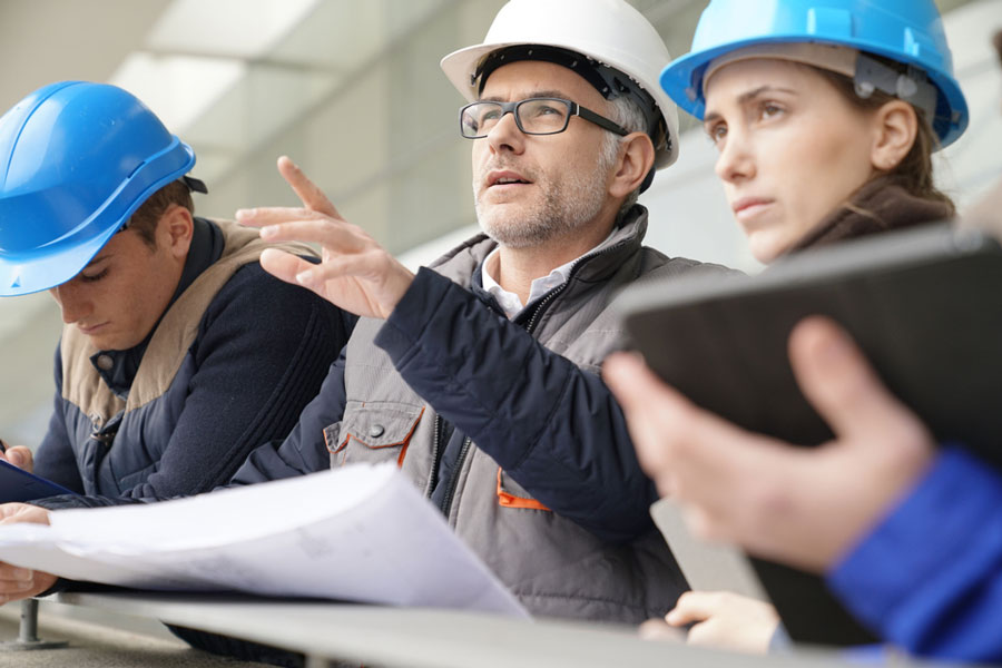 Group of worker in hardhats looking at plans